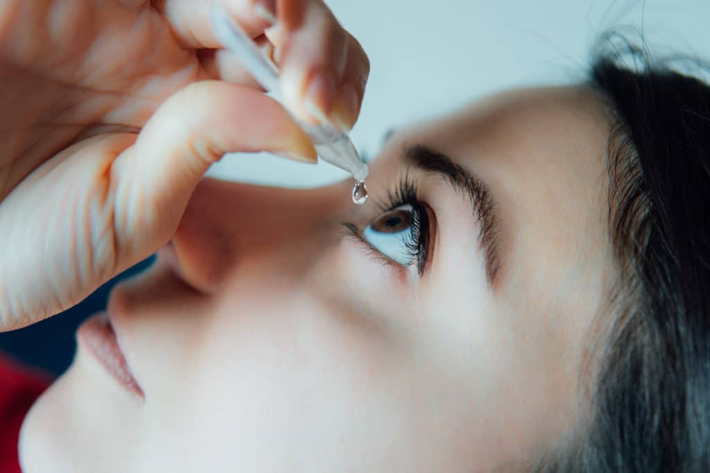 woman putting eye drops in her eye.